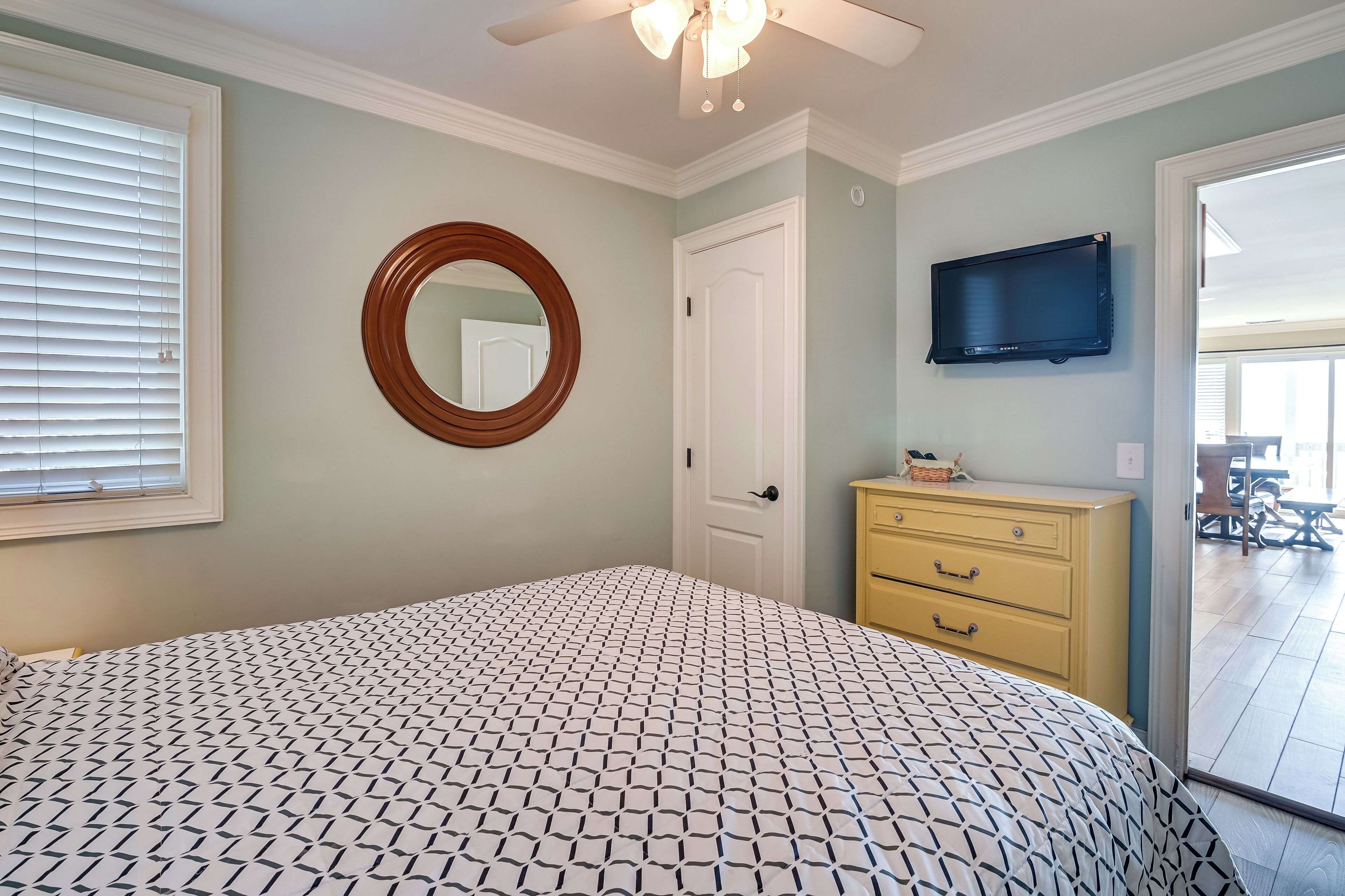 A bedroom with a bed, a dresser, a television, and a door.