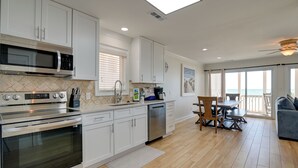 A modern kitchen with stainless steel appliances, white cabinetry, and a dining area with a view of the ocean. - Beachfront Murrells Inlet Home - Walk to Pier! (Murrells Inlet)