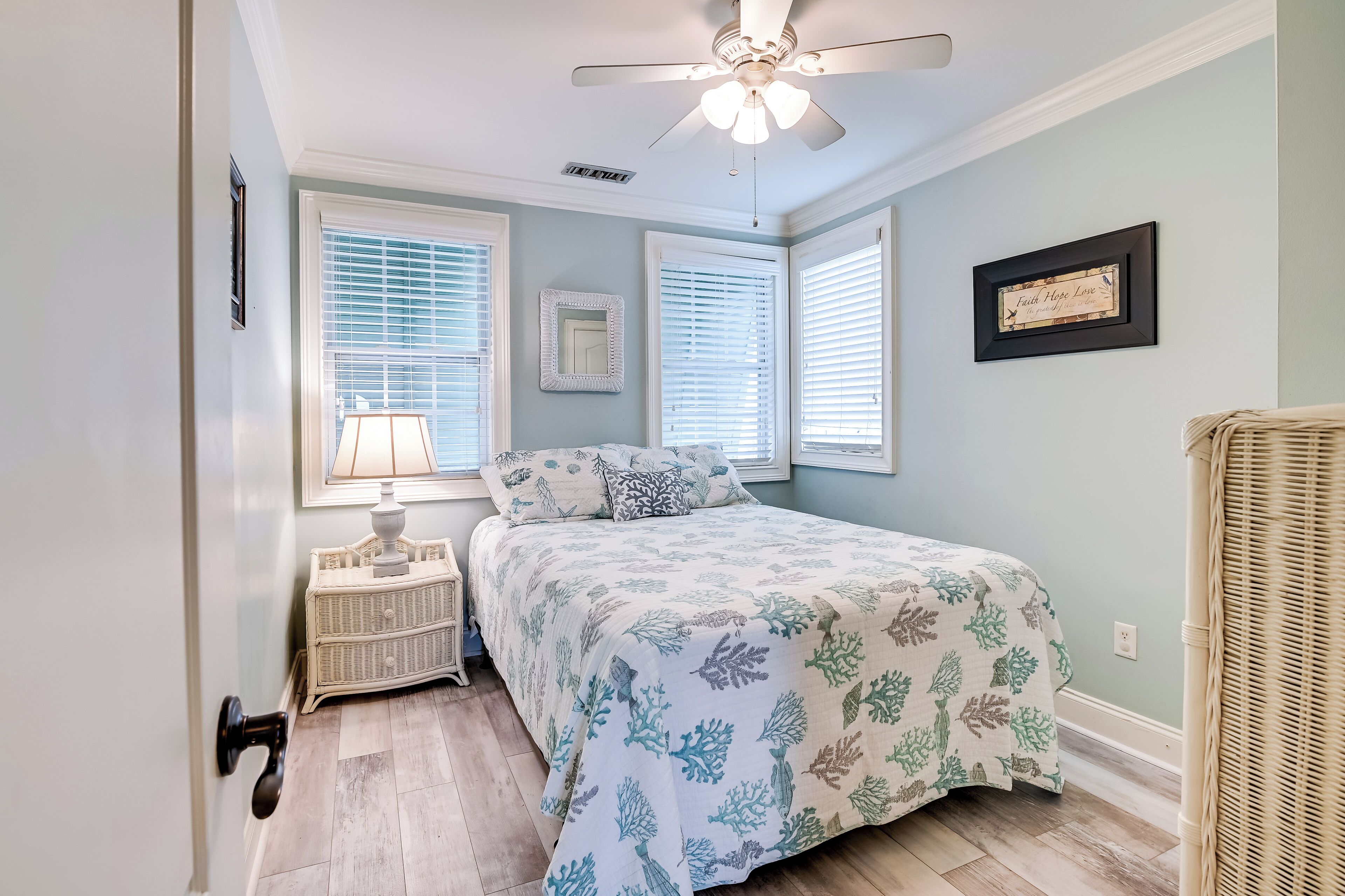 A bedroom with a bed, a nightstand, a lamp, a ceiling fan, and a framed certificate on the wall.