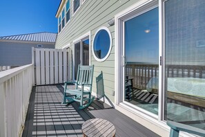 A balcony with a checkered floor, a wooden table, and two rocking chairs.