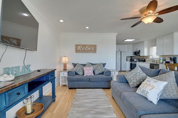 A modern living room with a grey sofa, a wooden coffee table, and a ceiling fan.