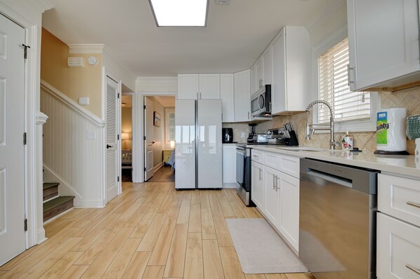 A modern kitchen with white cabinetry, a stainless steel refrigerator, and a dishwasher. - Beachfront Murrells Inlet Home - Walk to Pier! (Murrells Inlet)