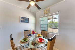 A dining area with a glass table, wicker chairs, and a ceiling fan. - Pet-friendly Venice Vacation Rental, 3 Mi to Beach (Venice)