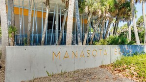 Betoninen kyltti, jossa lukee kultaisin kirjaimin: ”MANASOTA BEACH”.