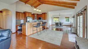 Une cuisine spacieuse avec des meubles en bois, un îlot central doté de tabourets, et un coin repas avec une table et des chaises.