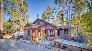 A two-story house with a stone foundation, a covered porch, and a garage. - 1 Mi to Lake: Home w/ Hot Tub & Gazebo in Big Bear (Big Bear Lake)