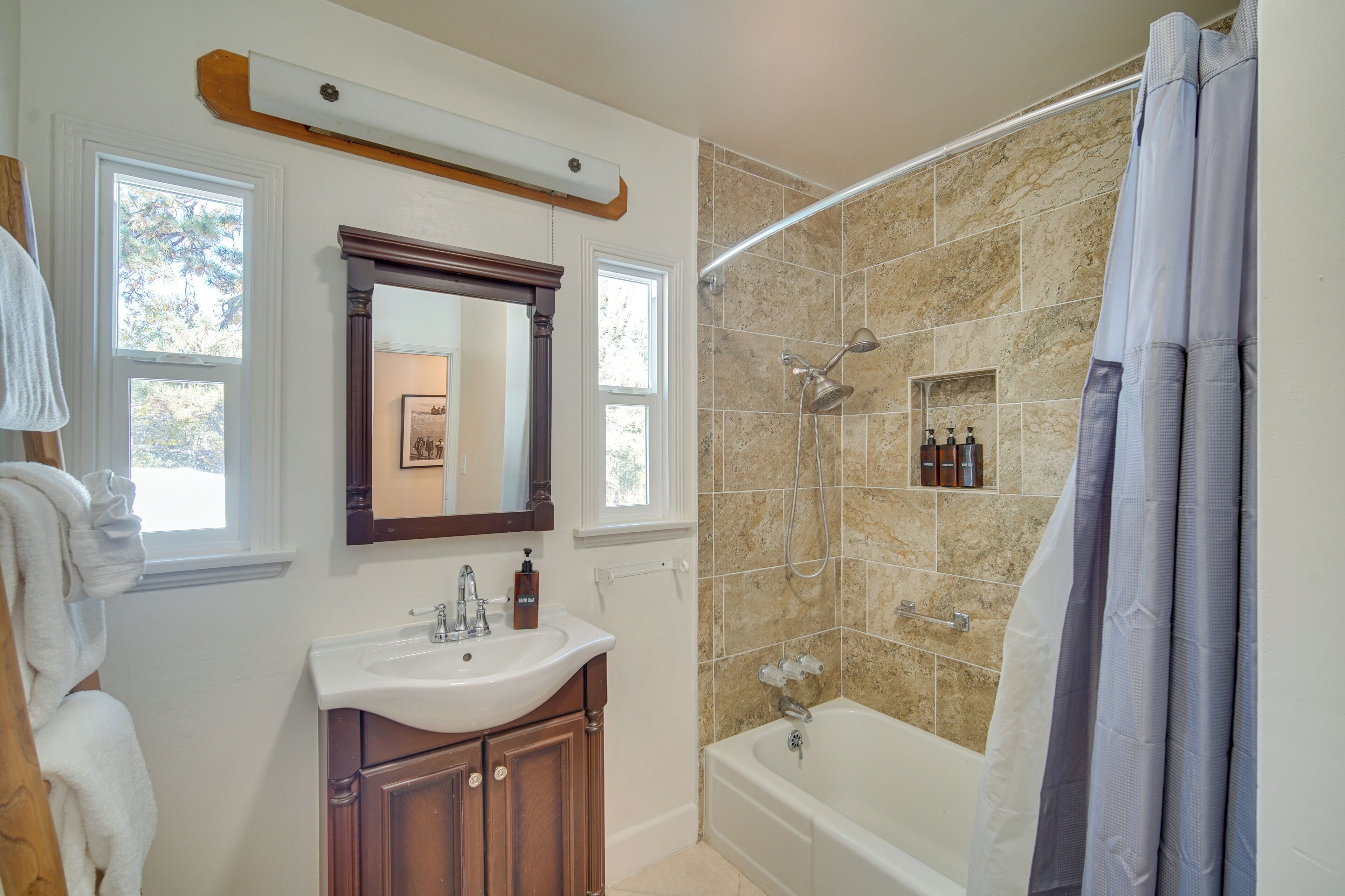 Une salle de bain équipée d’un lavabo, d’un miroir, d’un meuble-lavabo, d’une douche et d’une baignoire.