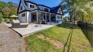 Une maison moderne à deux étages dotée d’un patio couvert, d’un espace salon extérieur et d’une cour clôturée.