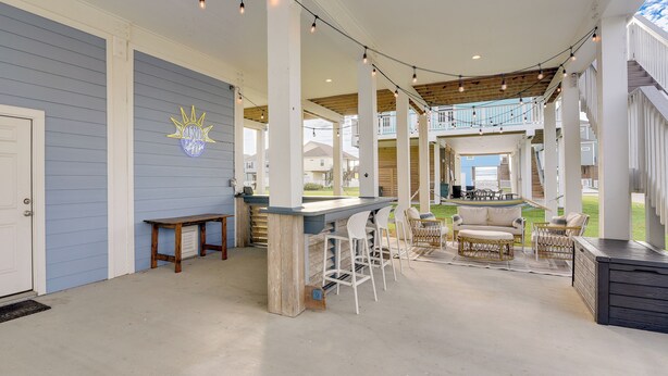 An outdoor patio area with a bar, seating, and a view of the neighborhood.
