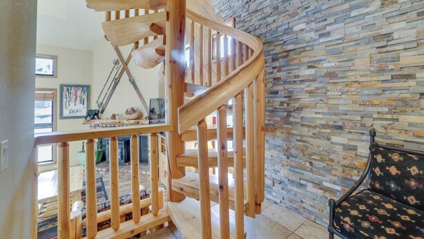 A wooden spiral staircase with a stone wall behind it. - Mammoth Lakes Condo - Steps to Ski Lift! (Mammoth Lakes)