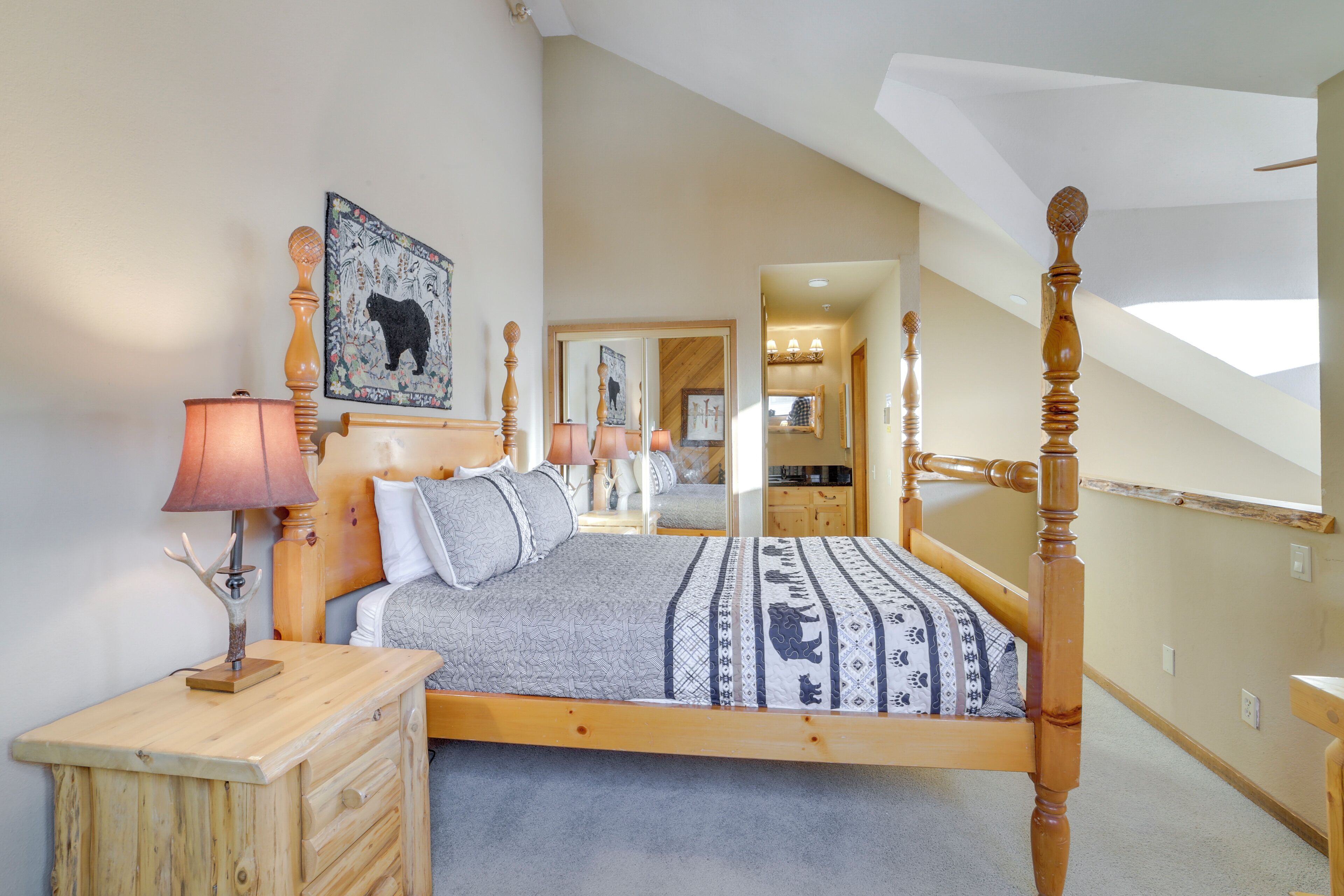 A bedroom with a wooden four-poster bed, a nightstand, a lamp, and a mirror.