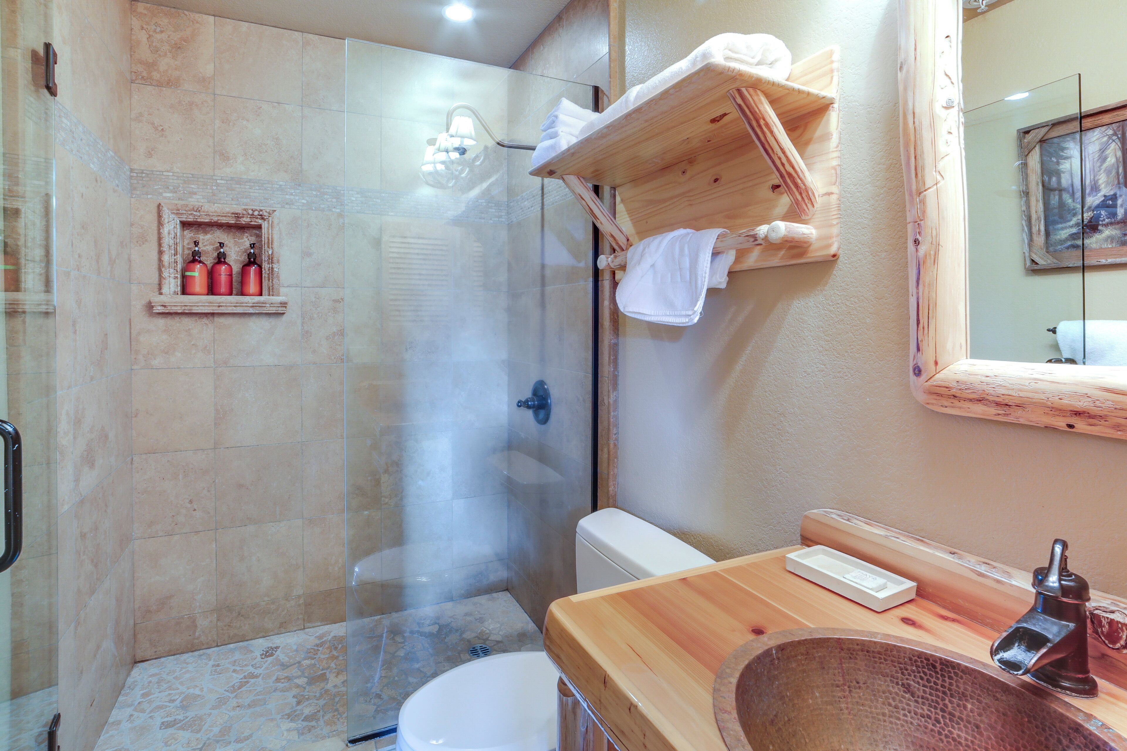 A bathroom with a glass-enclosed shower, a white toilet, and a wooden vanity with a sink.