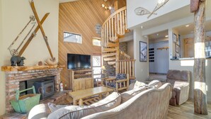 A spacious living area with a fireplace, wooden furniture, and a television. - Mammoth Lakes Condo - Steps to Ski Lift! (Mammoth Lakes)