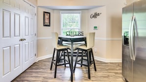 Une cuisine équipée d’une table à manger, de chaises, d’un réfrigérateur et d’une fenêtre avec des stores.