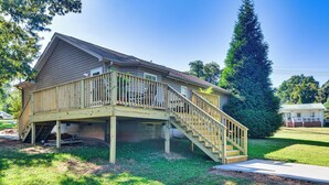 Une maison à deux étages dotée d’une terrasse en bois et d’un escalier menant à l’étage supérieur.