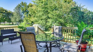 Une terrasse extérieure avec une table en verre entourée de chaises en osier, d’un canapé et d’une plante en pot.