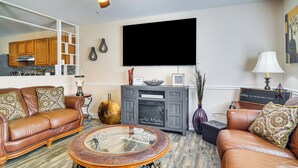 Un salon doté d’une cheminée, de canapés en cuir, d’une table basse en verre et d’un ventilateur de plafond.