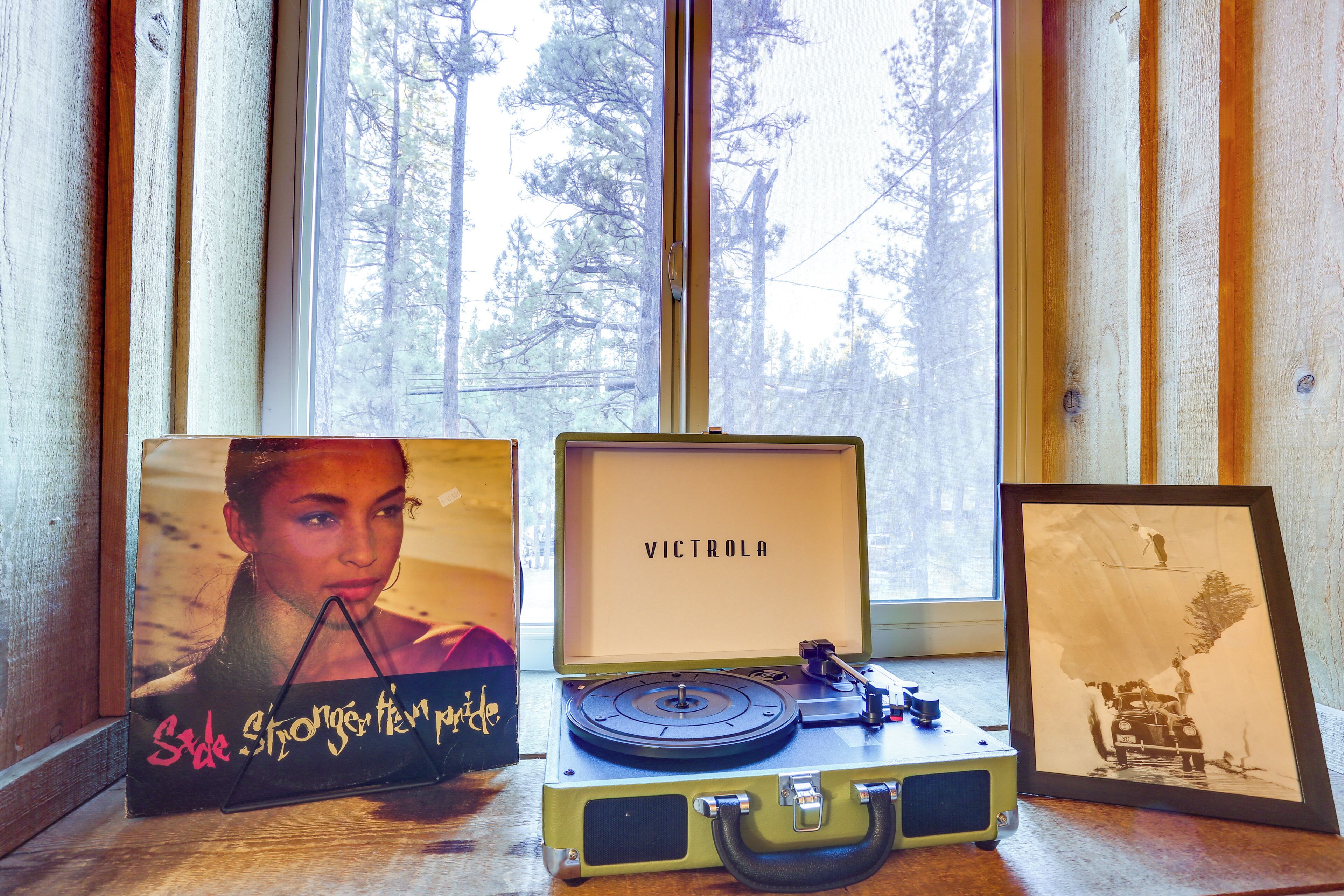 A vintage suitcase with a record player, a framed picture, and a box with a woman's portrait.