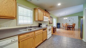 A kitchen with wooden cabinets, a microwave, a dishwasher, and a dining area with a table and chairs.