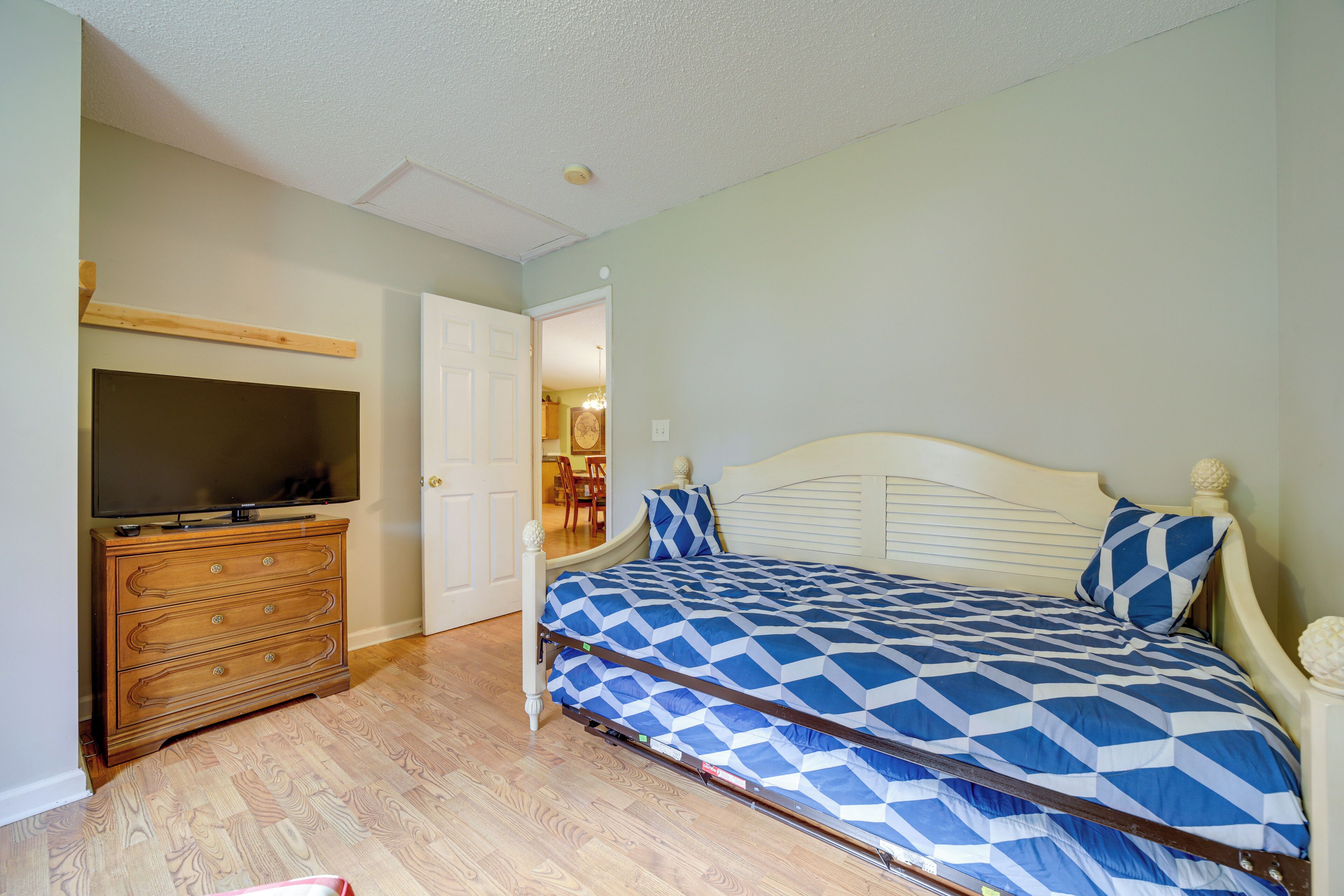 A bedroom with a bed, dresser, and television.
