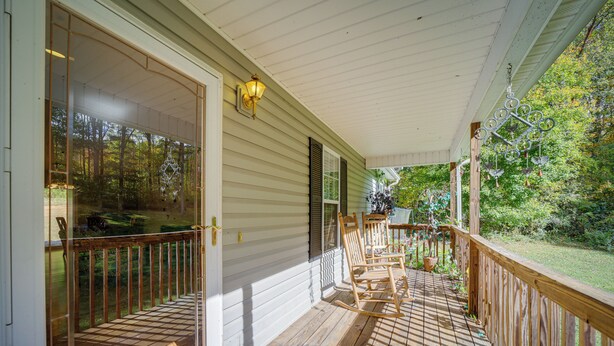 A wooden deck with a railing, a door, and a window.