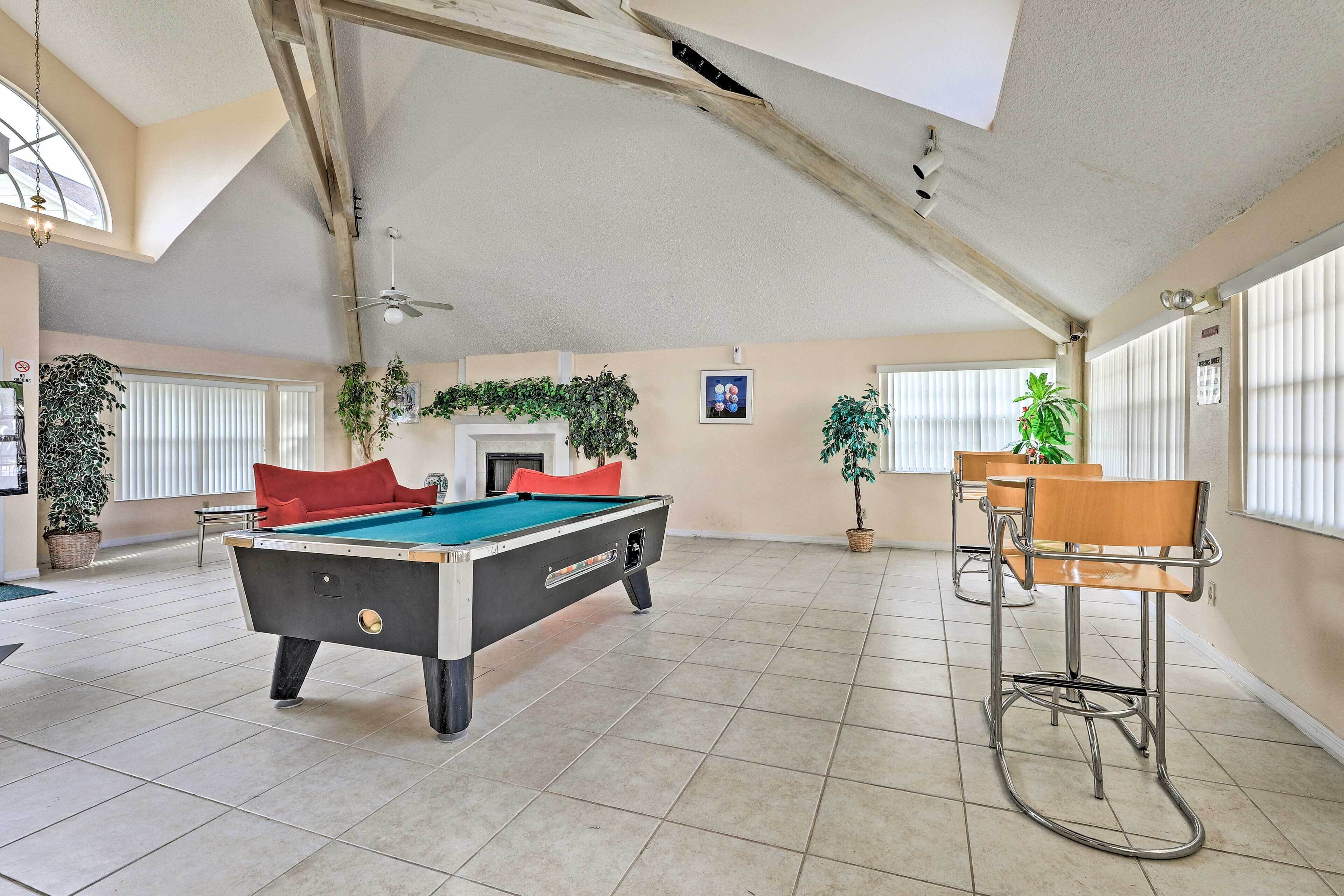 Un grand espace intérieur comprenant une table de billard, un coin salon et de grandes fenêtres.