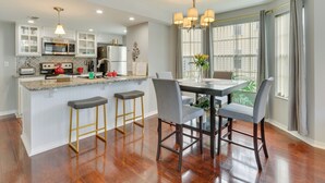 A modern kitchen with white cabinets, a granite countertop, and a central island with bar stools. - Kissimmee Condo w/ Perks: 6 Mi to Disney World! (Kissimmee)