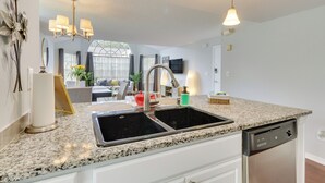 A kitchen with granite countertops, a double sink, and a dishwasher. - Kissimmee Condo w/ Perks: 6 Mi to Disney World! (Kissimmee)