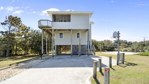 Un bâtiment à deux étages doté d’un balcon, d’un panier de basketball et d’un chemin en béton menant à l’entrée.