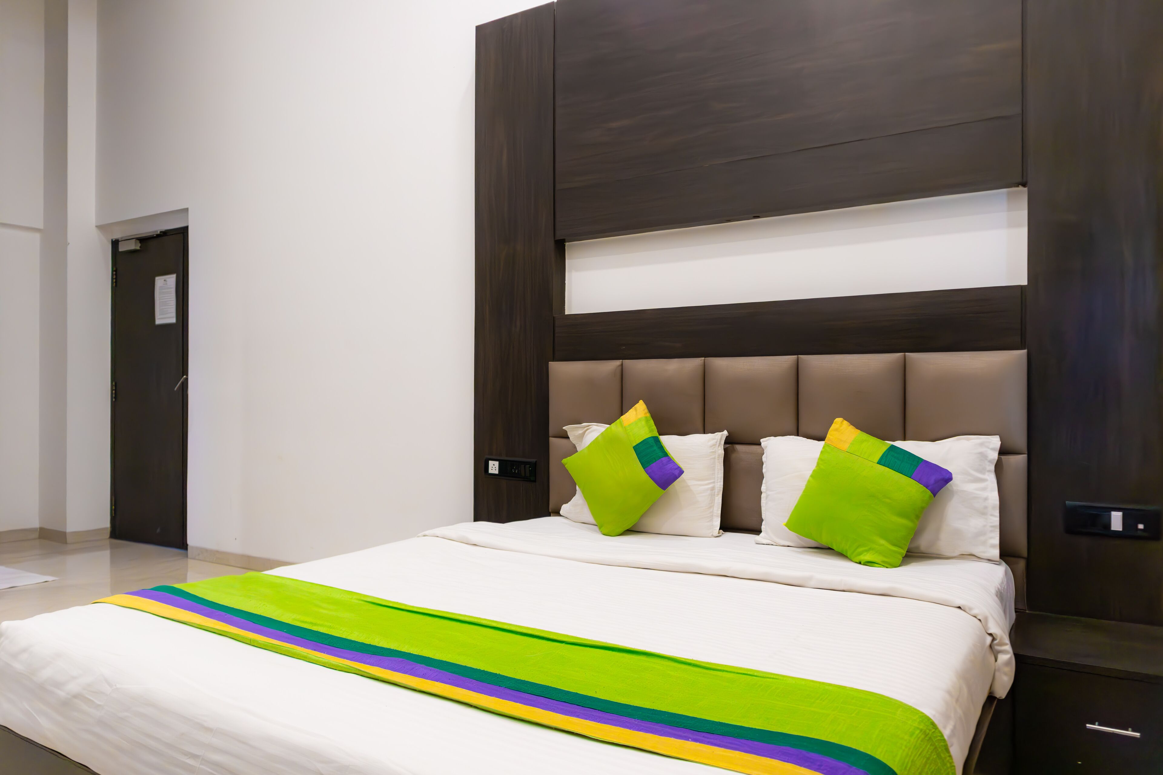 A hotel room with a large bed, a headboard, and two pillows.