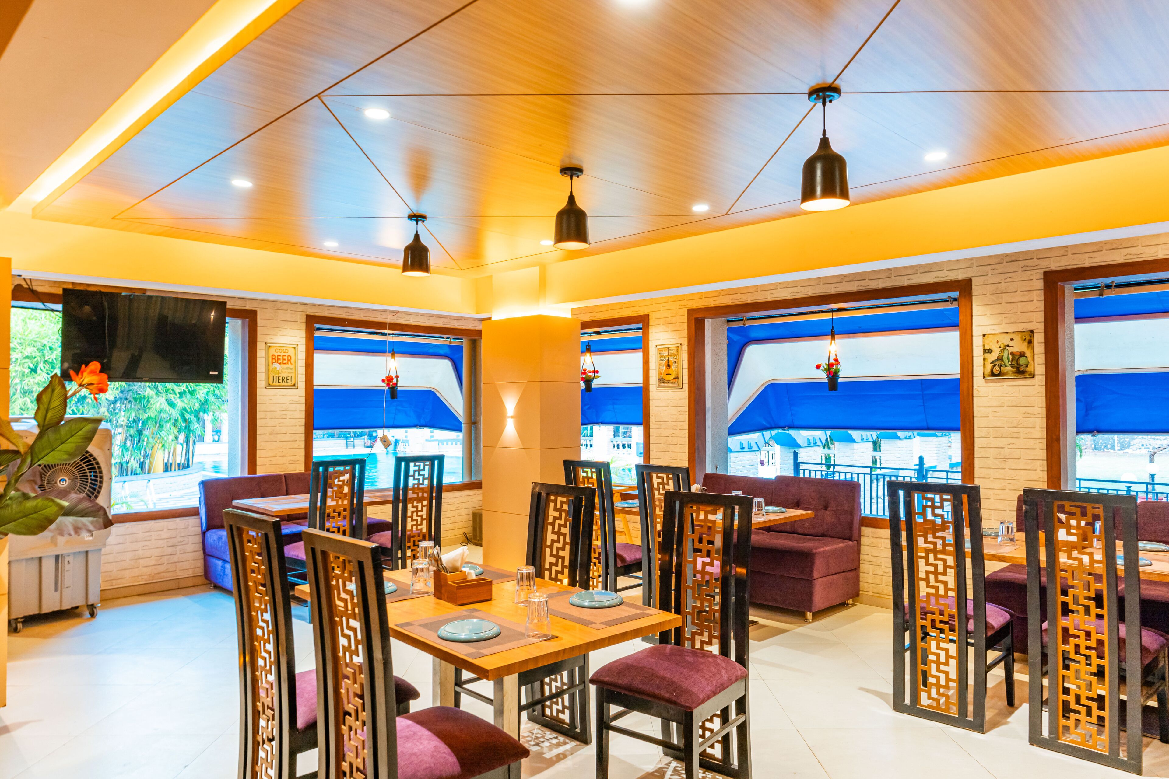 Un restaurante con techo de madera, ventanas de tono azul y asientos morados.