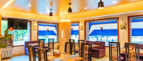 Un restaurante con techo de madera, ventanas de tono azul y asientos morados.