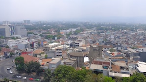 A cityscape with a mix of residential and commercial buildings, a prominent road, and some greenery.