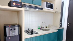 A compact kitchen with teal cabinetry, a GEA self-sanitizing gas stove, a microwave, and a sink.