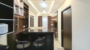 A modern hotel room with a central seating area, built-in wardrobe, and a large mirror. - Spacious And Elegant 1Br At Patraland Amarta Apartment (Ngaglik)