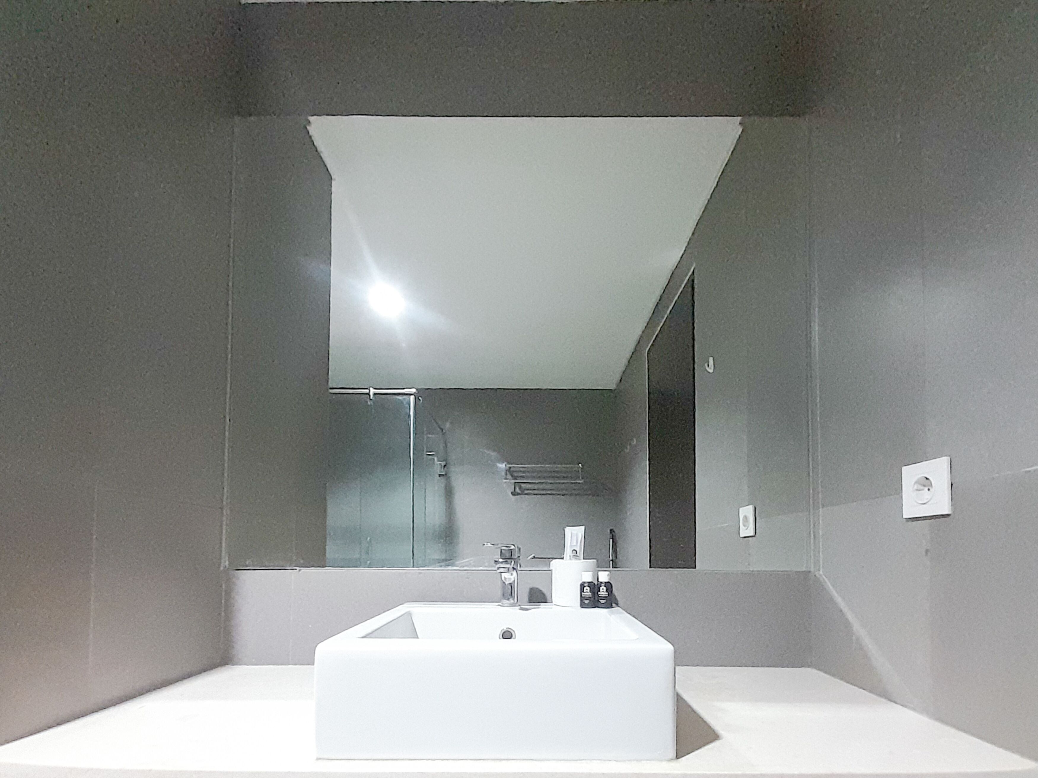 Une salle de bain moderne avec un lavabo rectangulaire, un grand miroir et un porte-serviettes.
