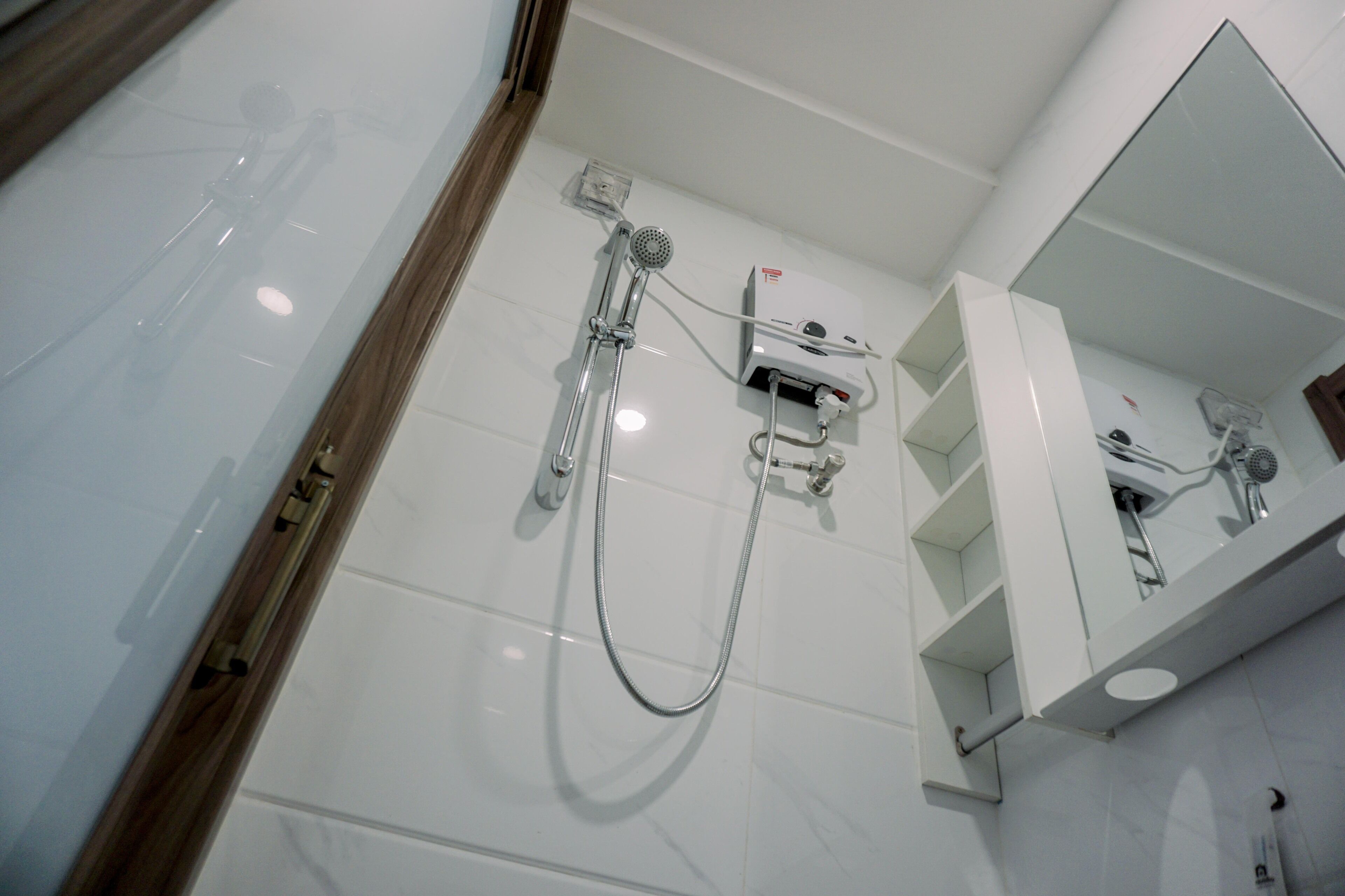 A modern bathroom with a shower, a mirror, and a white tiled wall.