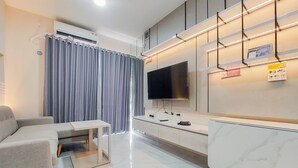 A modern living room with a sofa, a coffee table, a flat-screen TV mounted on the wall, and a built-in entertainment unit. - Elegant And Strategic 2Br Sky House Bsd Apartment Near Ice Bsd (Pagedangan)