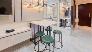 A modern kitchen with a white countertop, green bar stools, and a white refrigerator. - Elegant And Strategic 2Br Sky House Bsd Apartment Near Ice Bsd (Pagedangan)