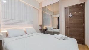 A modern hotel room with a large bed, a wooden door, and a mirror reflecting the room. - Elegant And Strategic 2Br Sky House Bsd Apartment Near Ice Bsd (Pagedangan)