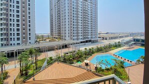 A high-rise building with multiple balconies, a rooftop pool area, and a landscaped terrace with stairs.