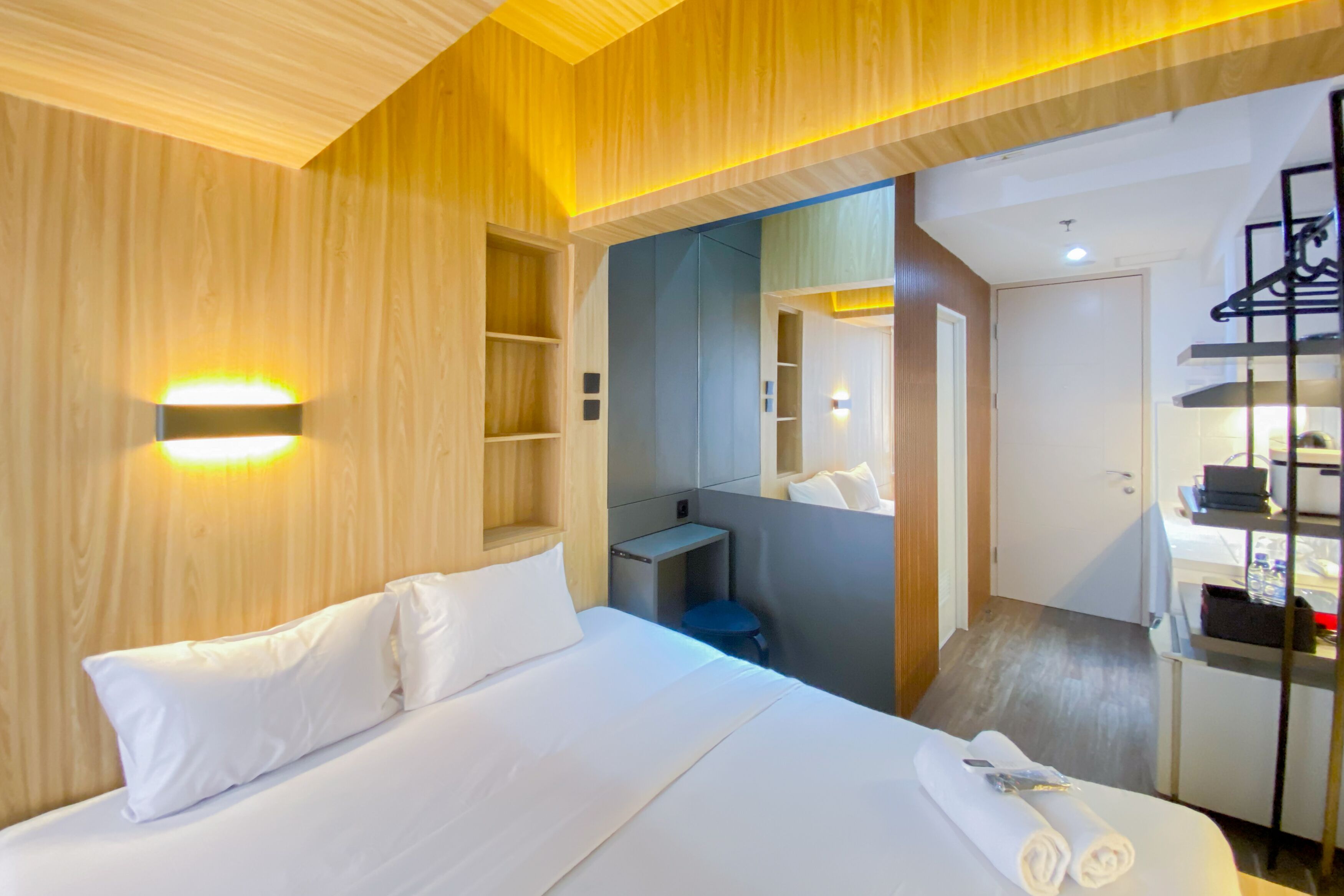A hotel room with a bed, bedside tables, a mirror, and a wardrobe.