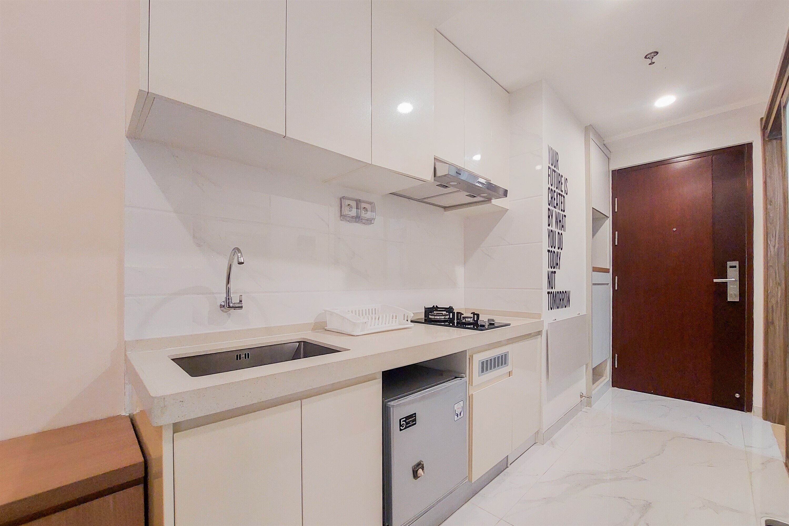 Una cucina moderna con lavello integrato, piano cottura e piccolo frigorifero.