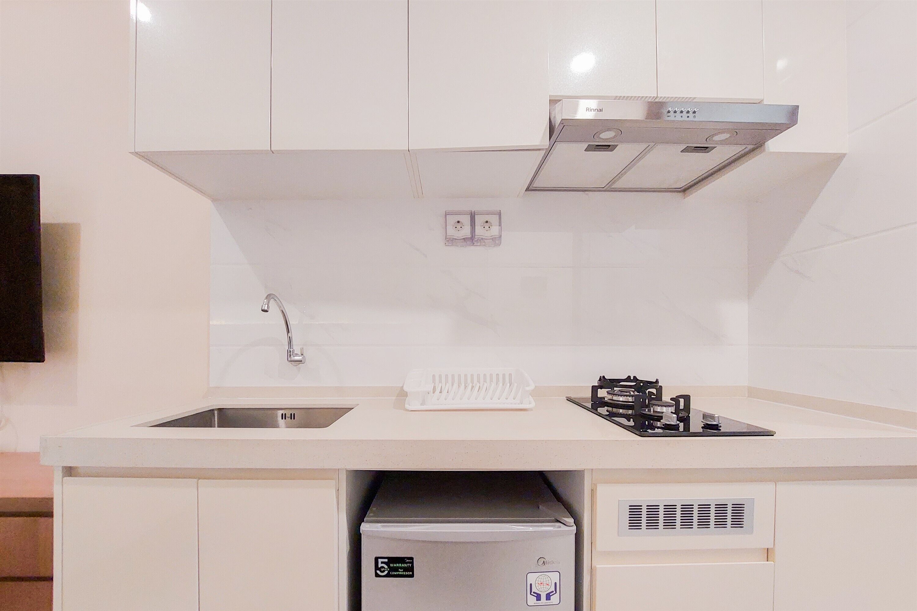 A modern kitchen with white cabinets, a stainless steel sink, and a built-in dishwasher.