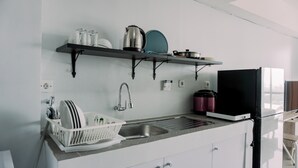 A modern kitchen with a built-in sink, a dish rack, and a black refrigerator.
