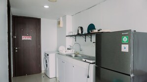 A compact kitchen with a washing machine, a stainless steel refrigerator, and a sink.