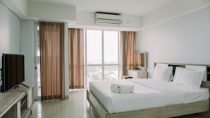 A hotel room with a large bed, a television, a desk, and a window with curtains.