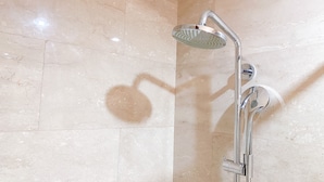 A shower with a handheld showerhead and a wall-mounted faucet. - Warm And Best Studio At Menteng Park Apartment (Jakarta)