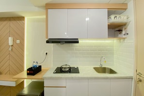 A compact kitchen with white cabinets, a stainless steel sink, and a built-in stove.