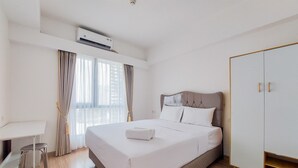 Ein Hotelzimmer mit einem Bett, einem Schreibtisch, einem Kleiderschrank und einer Klimaanlage.